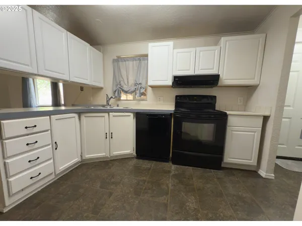 a kitchen with granite countertop white cabinets and stainless steel appliances