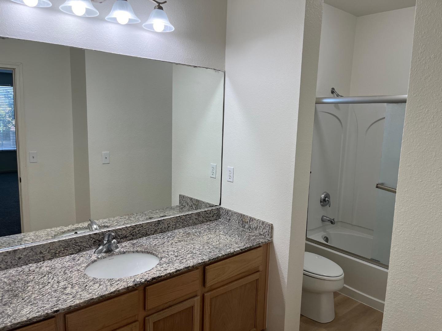 213 Pacifica Boulevard, Unit 202 Watsonville, CA 95076 - Photo 13 of 19 a bathroom with a granite countertop sink toilet and shower