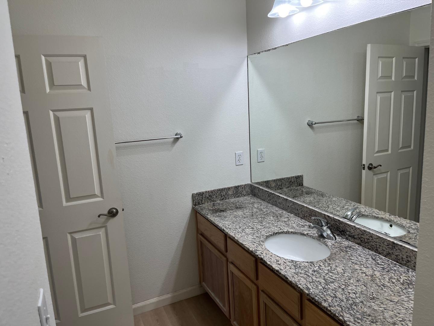 213 Pacifica Boulevard, Unit 202 Watsonville, CA 95076 - Photo 14 of 19 a bathroom with a granite countertop sink and a mirror