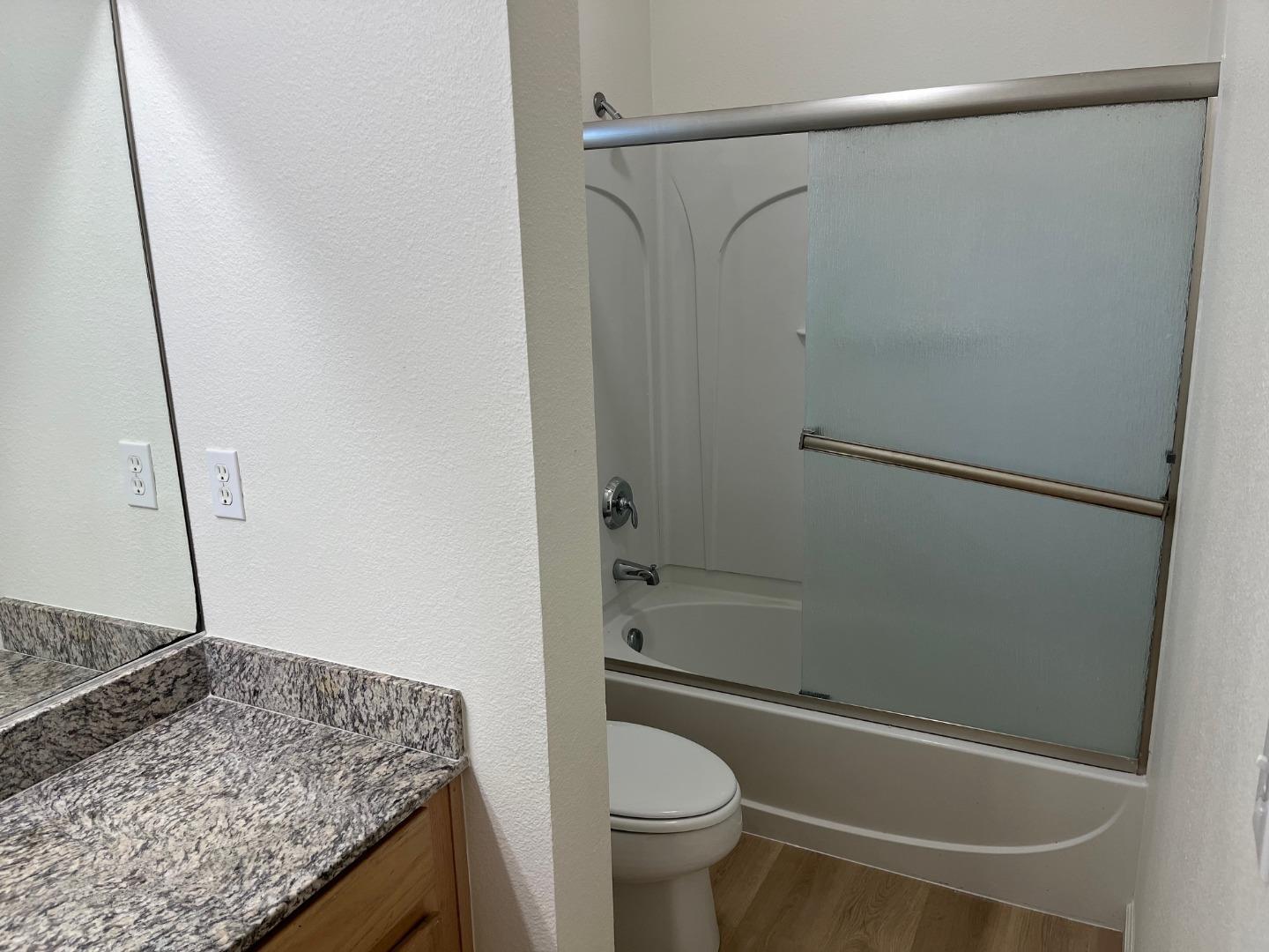 213 Pacifica Boulevard, Unit 202 Watsonville, CA 95076 - Photo 15 of 19 a bathroom with a granite countertop bathtub shower and toilet