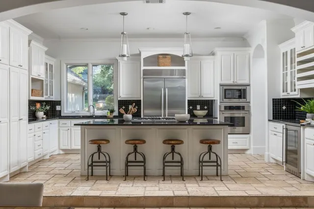a kitchen with stainless steel appliances granite countertop a table and chairs in it