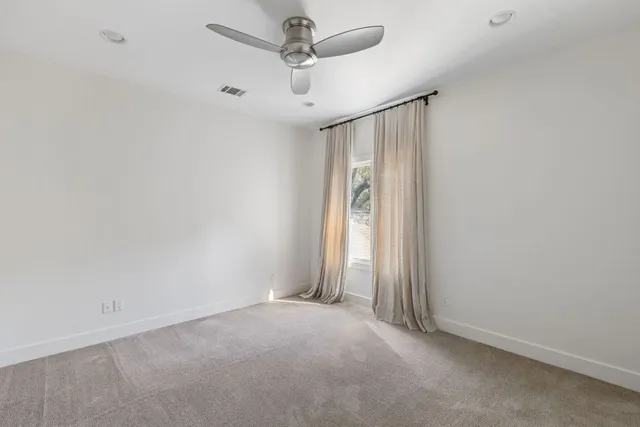 an empty room with a ceiling fan and a window