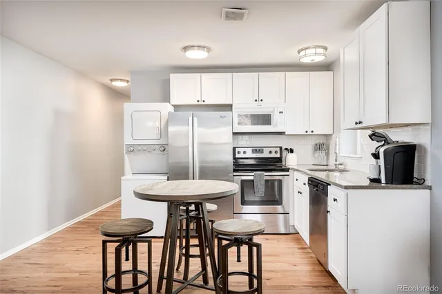a kitchen with stainless steel appliances a table chairs refrigerator and cabinets