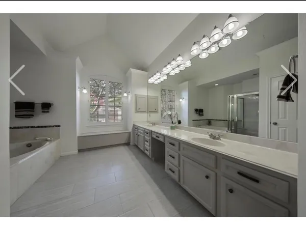 a spacious bathroom with a granite countertop sink a mirror a shower and a bathtub