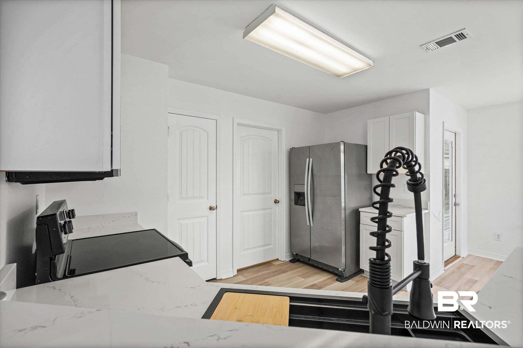 8980 Spring Grove North Mobile, AL 36695 - Photo 7 of 24 Kitchen featuring white cabinetry, light-toned wood-finish flooring, stainless steel appliances, and sleek countertops