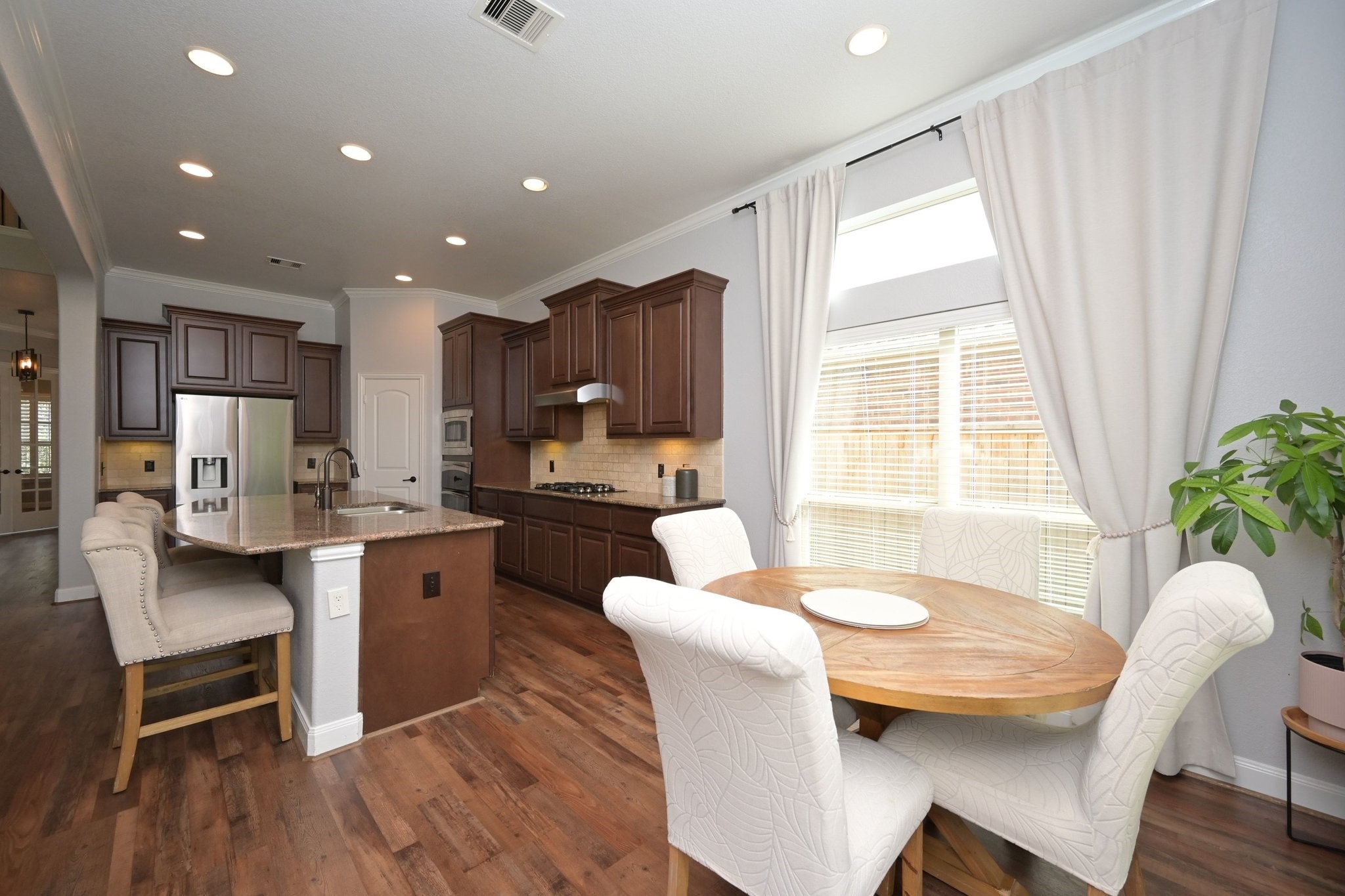 11 South Victoriana Circle Spring, TX 77389 - Photo 15 of 38 a living room with stainless steel appliances granite countertop furniture a kitchen island a stove a sink a refrigerator and a dining table with wooden floor