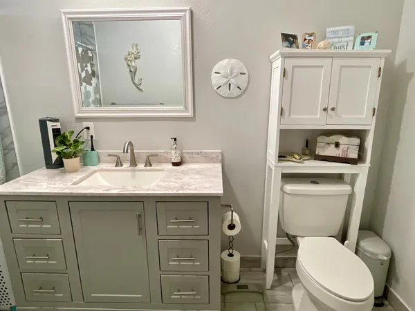 a bathroom with a granite countertop toilet sink and mirror