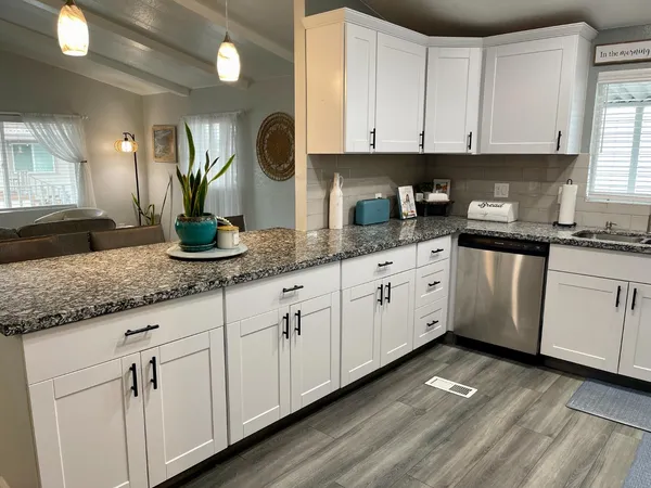 a kitchen with granite countertop white cabinets and white appliances