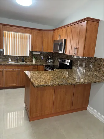 a kitchen with granite countertop a sink stove and cabinets