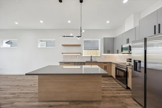 a large kitchen with kitchen island a large counter top stainless steel appliances and cabinets