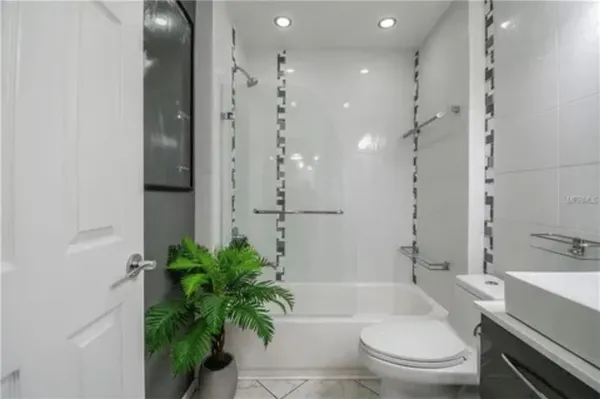 a bathroom with a granite countertop sink a toilet a tub and shower