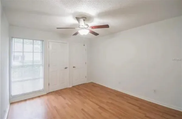 an empty room with closet and a ceiling fan