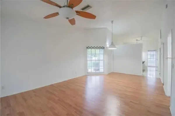 a view of an empty room with a window and wooden floor