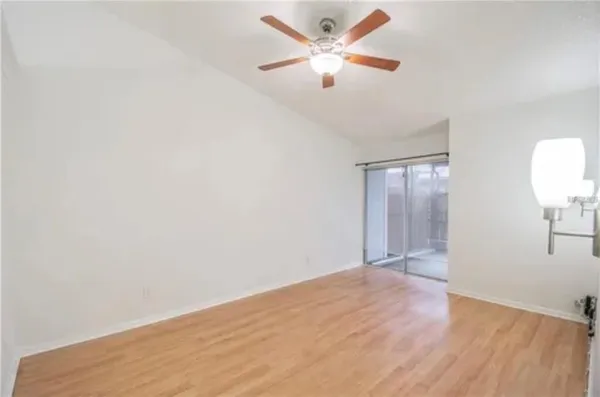 an empty room with wooden floor fan and windows