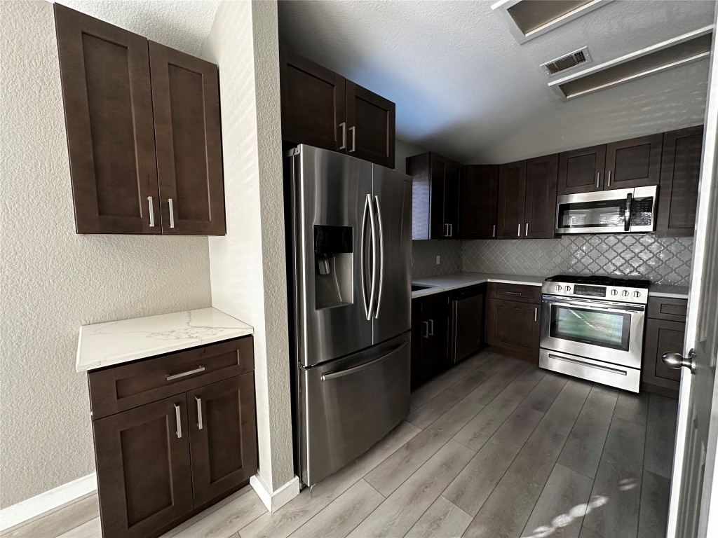 17733 Loch Linnhe Loop Pflugerville, TX 78660 - Photo 5 of 16 a kitchen with granite countertop stainless steel appliances and wooden cabinets
