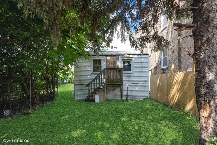 5943 South Aberdeen Street Chicago, IL 60621 - Photo 7 of 8 a view of a backyard with wooden fence and a large tree