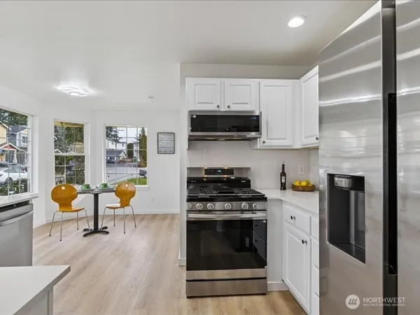 a kitchen with stainless steel appliances a stove a sink a refrigerator cabinets and a dining table