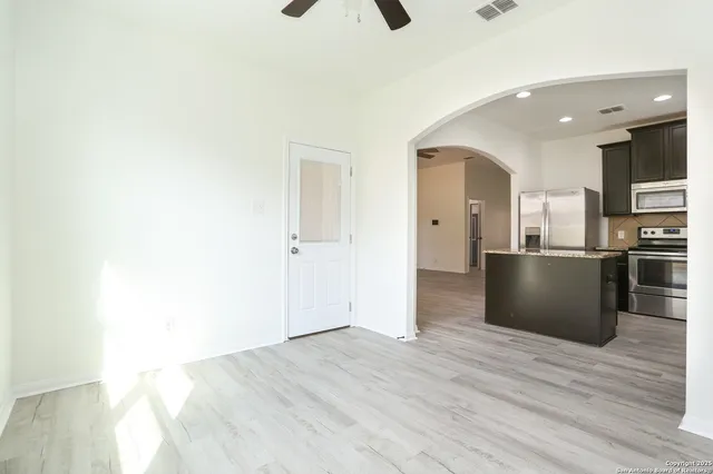 a view of kitchen and empty room with wooden floor