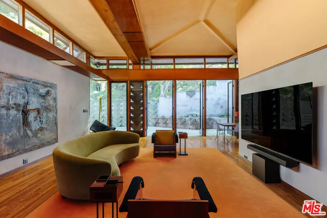 a living room with furniture a flat screen tv and a floor to ceiling window