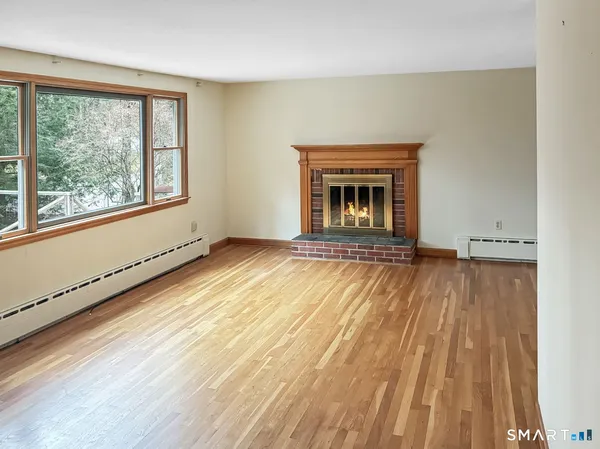 a view of an empty room with a window and wooden floor