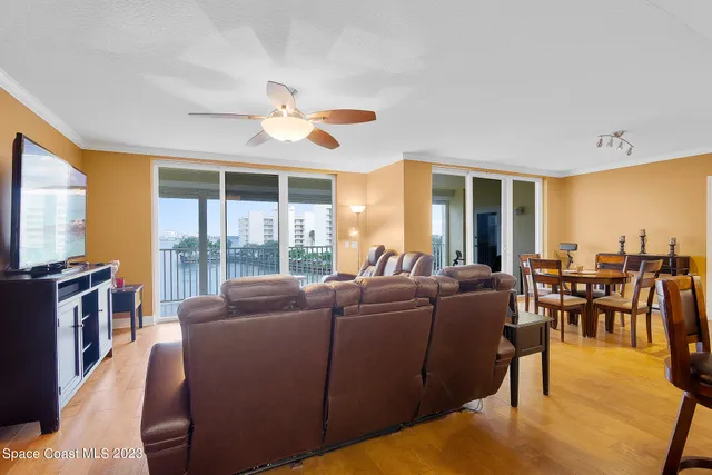 a living room with couches and a dining table with wooden floor