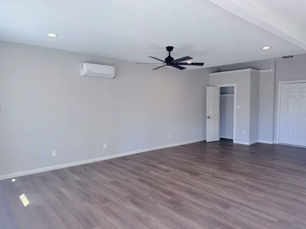 a view of an empty room with wooden floor and a ceiling fan