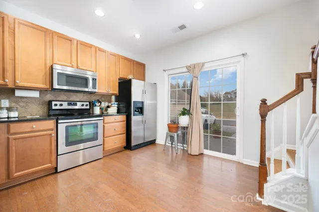 a kitchen with granite countertop a refrigerator and wooden cabinets