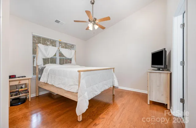 a bedroom with a bed and a flat tv screen on the dresser