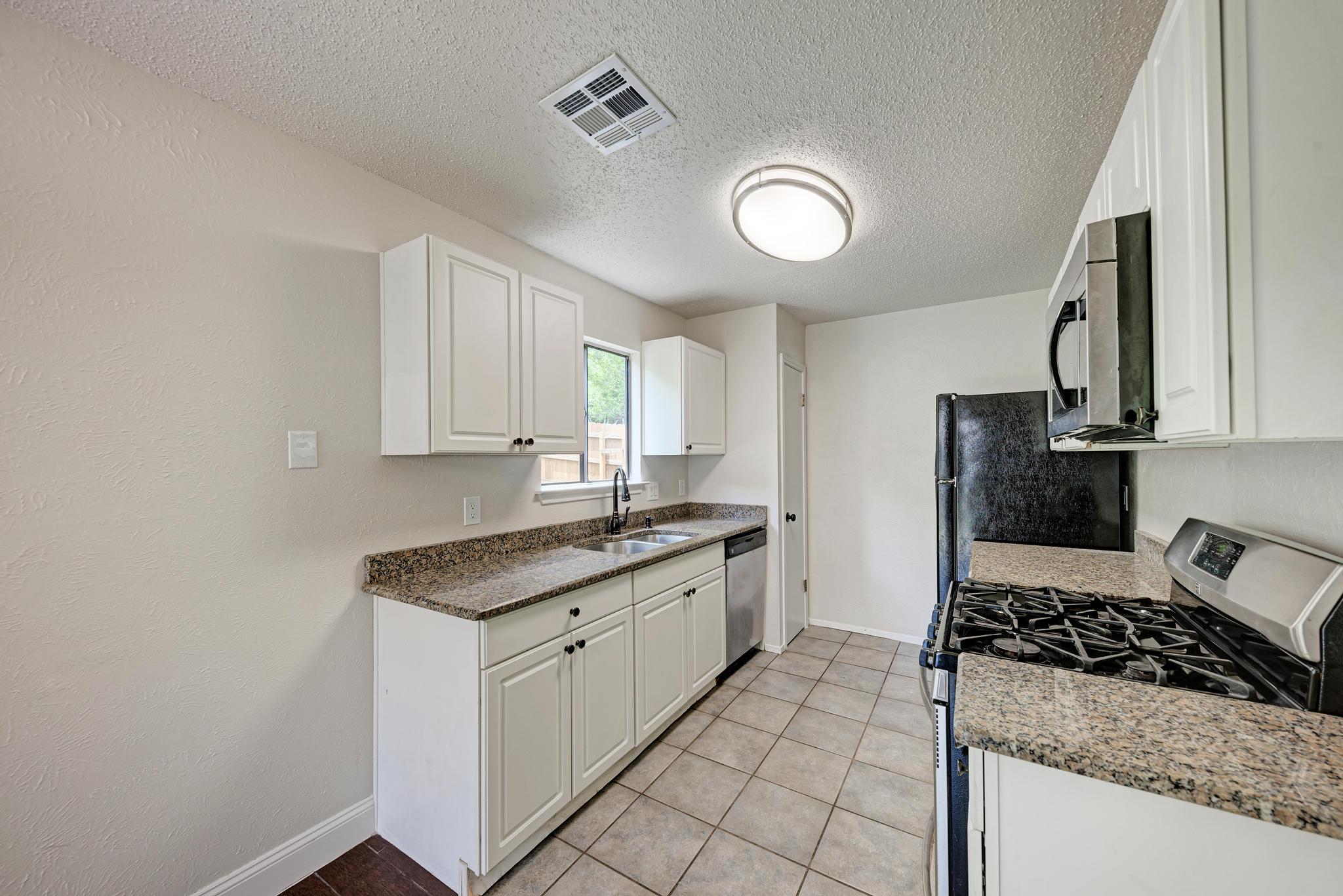 12108 Carnforth Drive Austin, TX 78753 - Photo 13 of 33 a kitchen with granite countertop a stove sink and cabinets