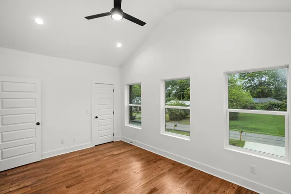 an empty room with wooden floor and windows