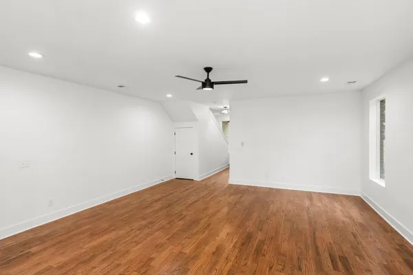 an empty room with wooden floor and ceiling fan
