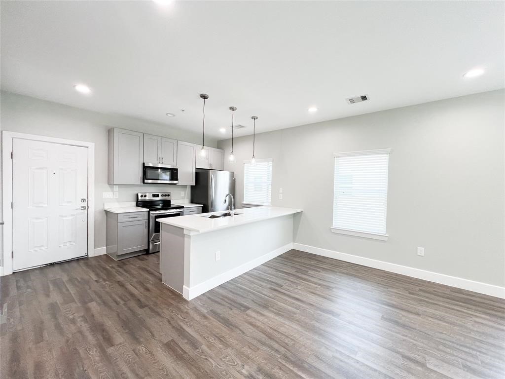 144 West 5th Street, Unit B Kemah, TX 77565 - Photo 16 of 22 a kitchen with stainless steel appliances a white cabinets and wooden floor
