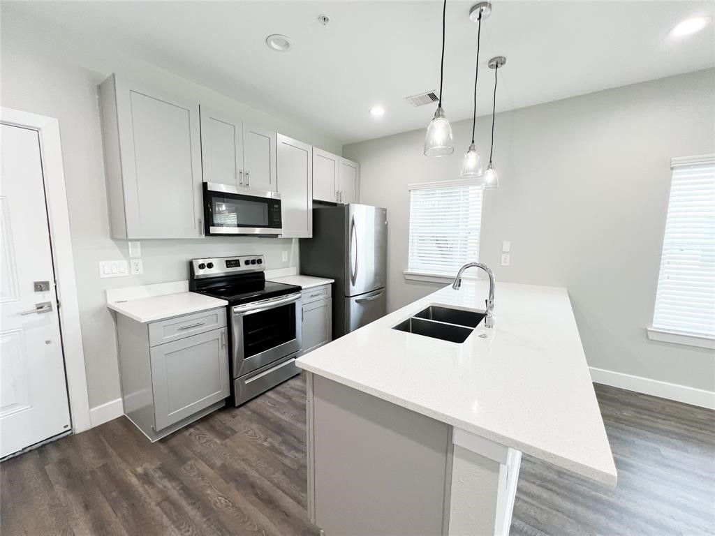 144 West 5th Street, Unit B Kemah, TX 77565 - Photo 6 of 22 a kitchen with kitchen island white cabinets stainless steel appliances and wooden floor