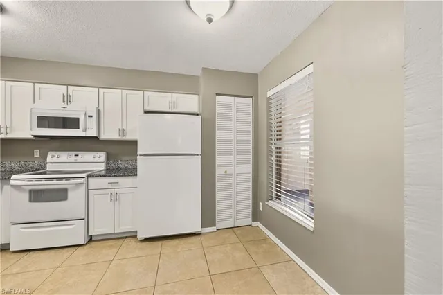 a kitchen with white cabinets and white appliances