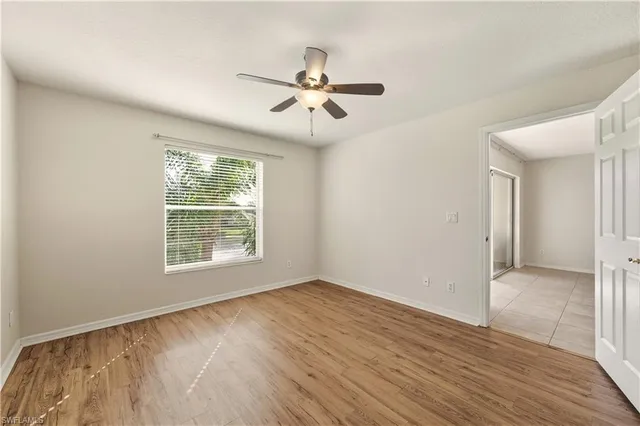 a view of empty room with wooden floor and fan