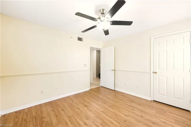 an empty room with wooden floor fan and windows