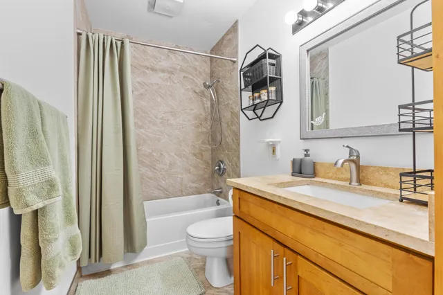 a bathroom with a granite countertop sink a toilet and a bathtub