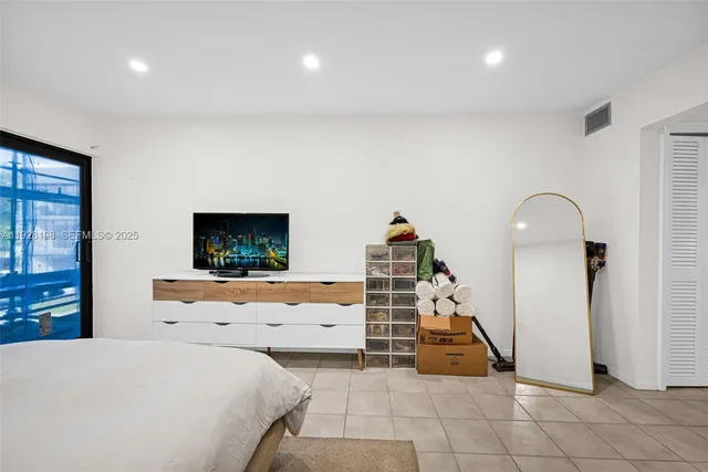 a bedroom with bed and a flat tv screen on dresser