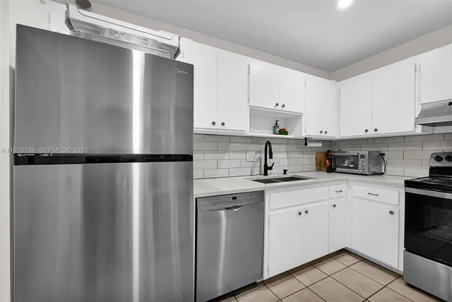 a kitchen with stainless steel appliances granite countertop white refrigerator a sink and white cabinets