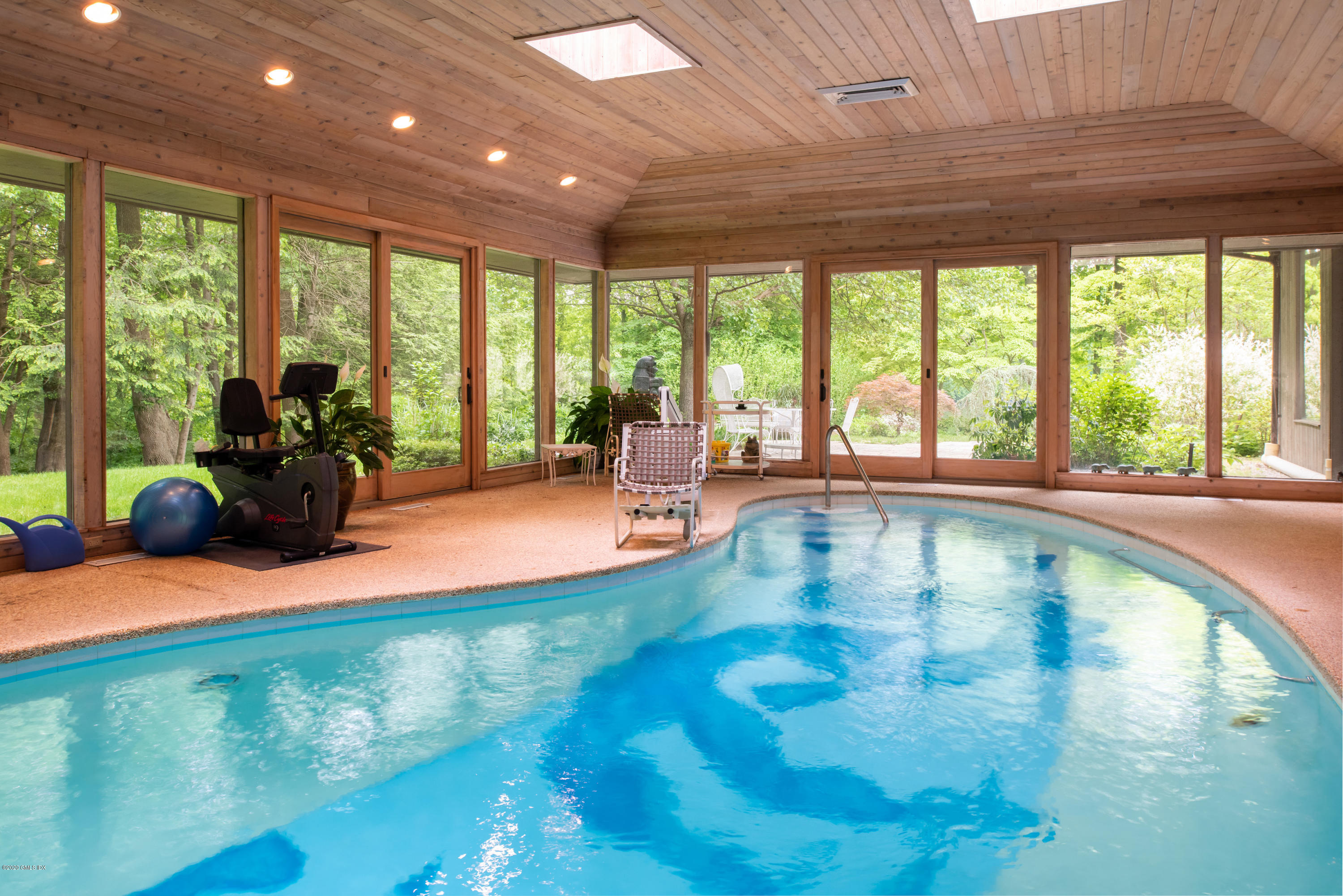 51-0 Burying Hill Road Greenwich, CT 06831 - Photo 21 of 47 a swimming pool with lawn chairs and couches with wooden floor