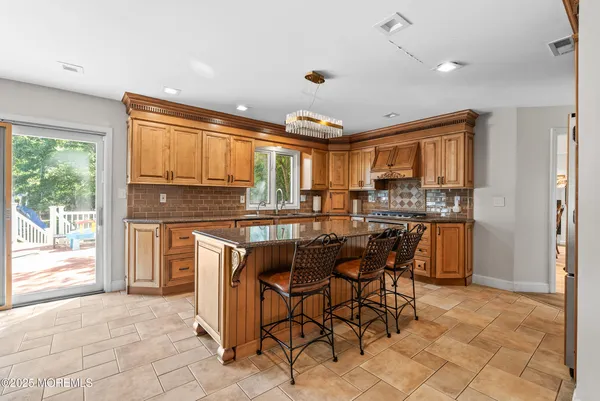 a kitchen with kitchen island granite countertop wooden cabinets a refrigerator a stove a dining table and chairs