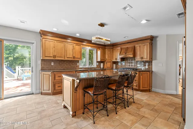 a kitchen with kitchen island granite countertop wooden cabinets a refrigerator a stove a dining table and chairs