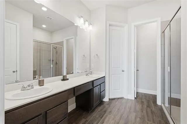 a bathroom with a double vanity sink a mirror and a shower
