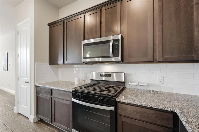a kitchen with stainless steel appliances granite countertop white cabinets and a stove top oven