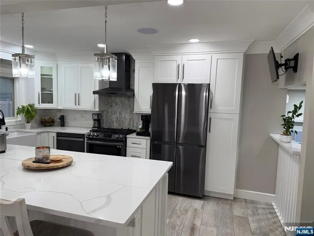 a kitchen with stainless steel appliances a refrigerator a sink a stove a microwave a counter and chairs