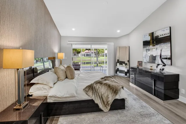 a bedroom with a bed a flat screen tv and a large window with the dresser