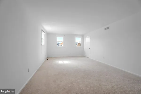 an empty room with windows and chandelier fan
