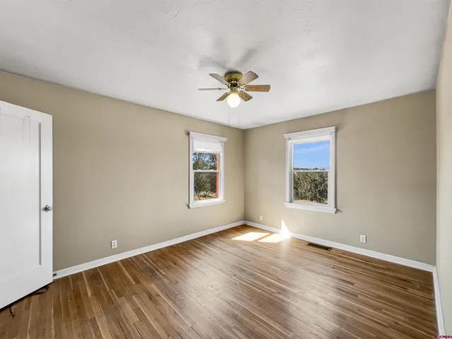 a view of an empty room with a window and wooden floor