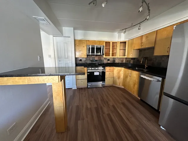 a kitchen with granite countertop a refrigerator stove top oven and sink