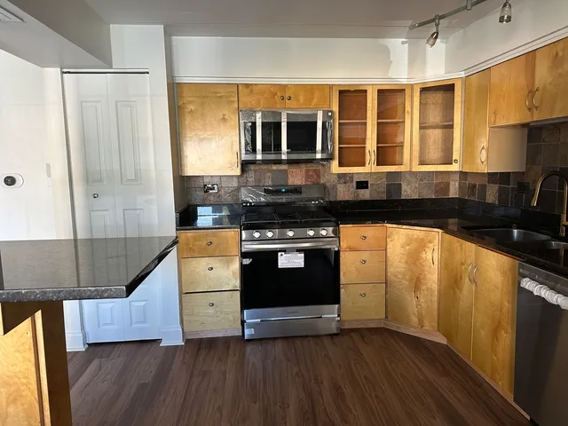 a kitchen with stainless steel appliances granite countertop a stove and a wooden cabinets